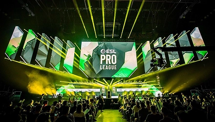 Een groot podium tijdens het ESL Pro League-esports-evenement, verlicht met groene en gele lampen. Een enthousiast publiek vult de arena en straalt opwinding en energie uit